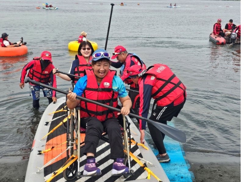 兩人站上立槳板，隨著浪花緩緩滑行，展現「友愛共好」的實踐畫面，也讓現場響起熱烈掌聲。