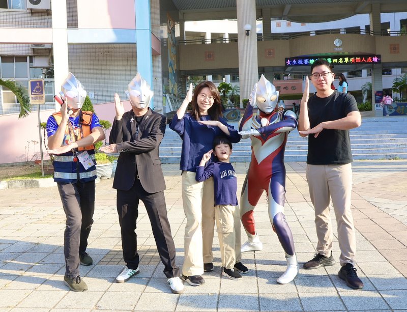 校長王彥嵓與家長會長、蘇守懌及師長家長扮演的超人力霸王，在校門口迎接學生開學。（漾新聞記者陳雯萍攝）
