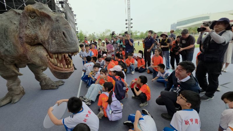教育局長吳立森帶領鳳山區忠孝國小與新甲國小學童超幸運，在記者會中，近距離與恐龍互動，超新體驗，既驚嚇又開心。(漾新聞記陳雯萍攝)
