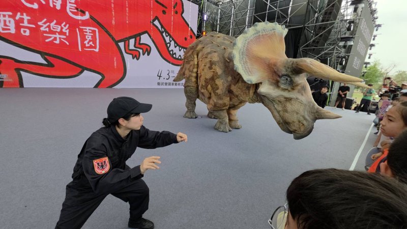 高雄市衛武營有恐龍，而且還是「會動的恐龍」，高雄兒童節，吳立森帶領學童與擬真恐龍同歡。(漾新聞記者陳雯萍攝)