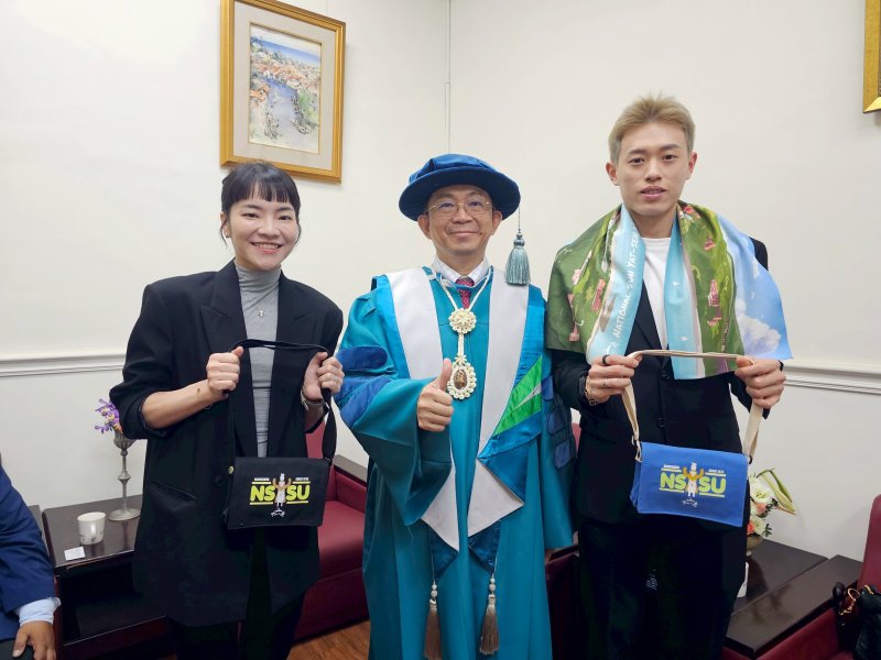 國立中山大學校長李志鵬(中)致贈羽球國手林俊易(右)及甫新婚的夫人程郁捷中山大學小書包與運動毛巾,以及出國實用的行李束帶與吊牌,祝福比賽順利。 國立中山大學校長李志鵬(中)致贈羽球國手林俊易(右)及甫新婚的夫人程郁捷中山大學小書包與運動毛巾,以及出國實用的行李束帶與吊牌,祝福比賽順利。