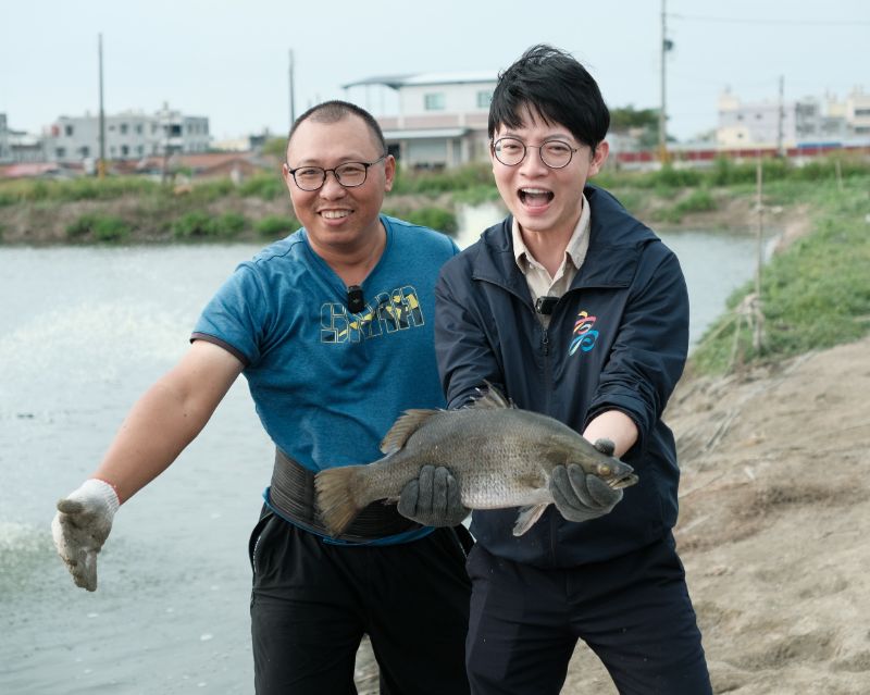 青年局長林楷軒（右）訪視魚塭，養殖達人許懷聰（左）現場解說金目鱸魚養殖情形，並展示平均重達4斤的肥美鱸魚，展現高雄優質水產能量。